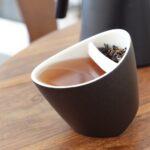Black tilting teacup filled with pu erh orange tea