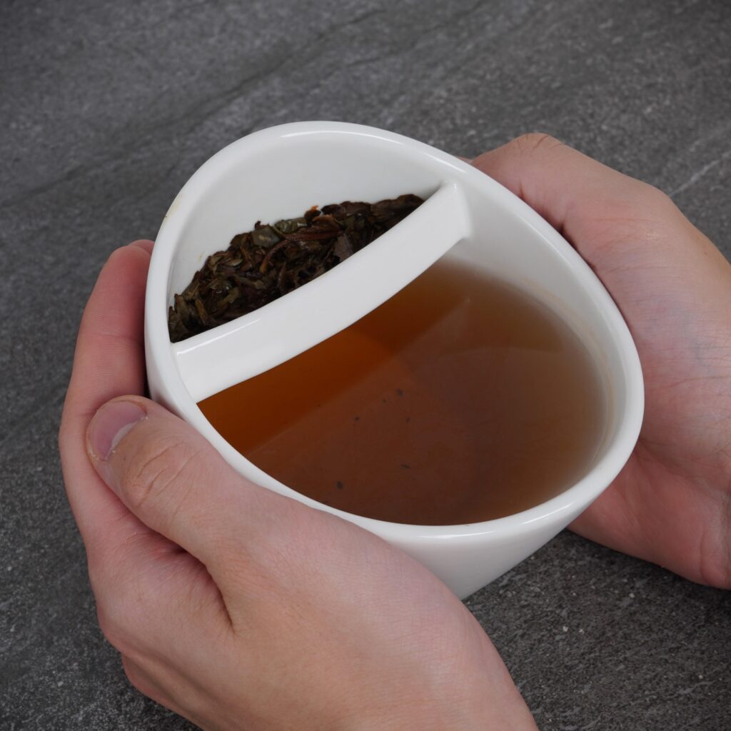 Person holding tilting teacup with both hands