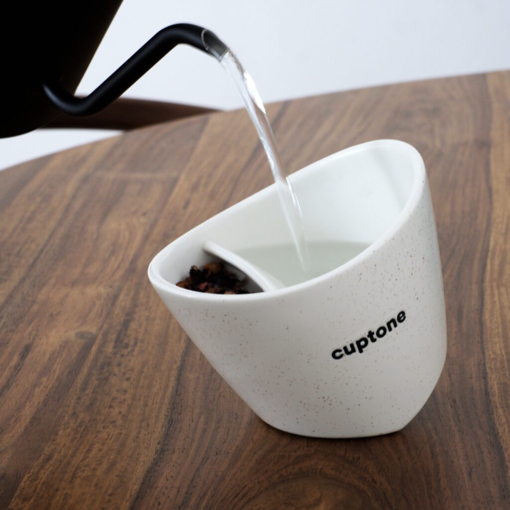 Pouring hot water into tilting teacup using gooseneck kettle